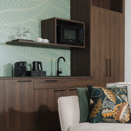 Moderne K&uuml;che in dunklem Holz, mit Mikrowelle, Kaffeemaschine, Teekocher und Waschbecken.